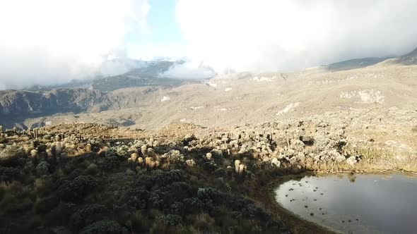 Pull back aerial reveal shot over mountains in South America with sun and cloud