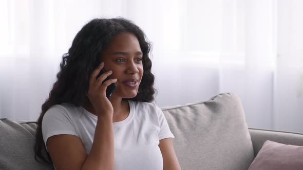 Happy Black Teen Girl Talking On Cellphone While Relaxing On Couch