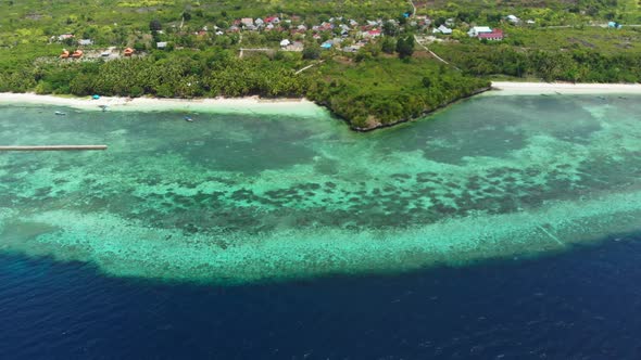 Aerial: Flying over tropical beach turquoise water coral reef , Indonesia