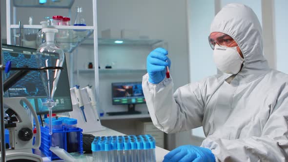 Scientist in Sterile Chemistry Suit Analysing Blood Sample From Test Tub
