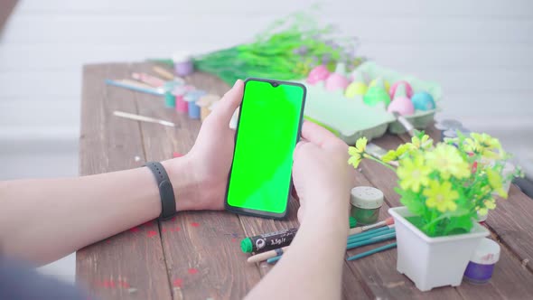 A Man Prepares for Easter Paints Easter Eggs and Uses a Smartphone with Chroma Key