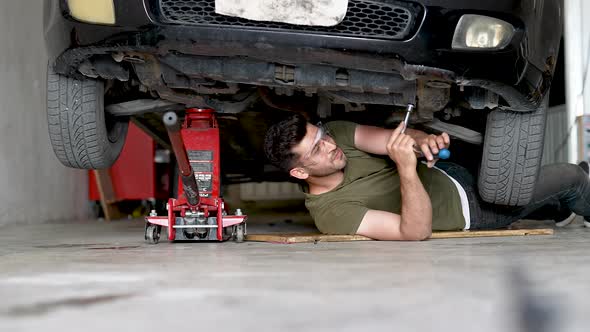 Male Car Mechanic Fixes a Vehicle From Below