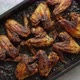 Grilled Chicken Wings in Spices in Black Metal Baking Tray on Stone Table - VideoHive Item for Sale