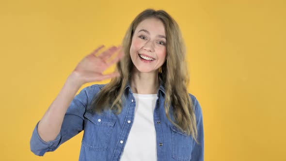 Young Pretty Girl Waving Hand to Welcome on Yellow Background
