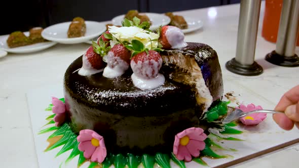 Men's Hand Takes Out a Piece of Sliced Chocolate Pie with Strawberries