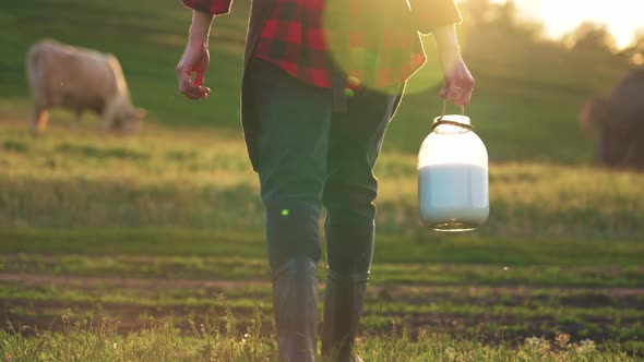 Woman Stands in Meadow of Farm with Pasture for Cow with a Milk Can in Hand for Milking Cattle