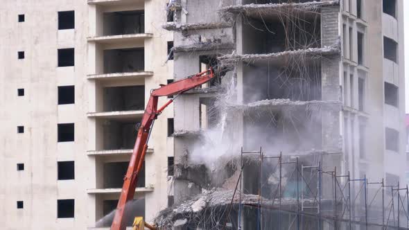 Destroying Old Concrete House Using Mechanical Arm of Bulldozer on Construction Site alt