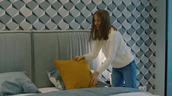 Joyous Woman Catching Decorative Pillows and Putting Them on Bed