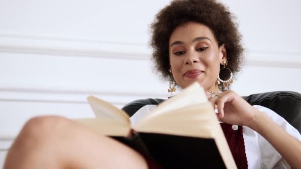 A close-up view of a beautiful woman holding a book while using mobile