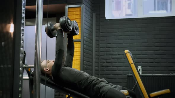 Athletic Man in the Gym Performing the Exercise with Dumbbells