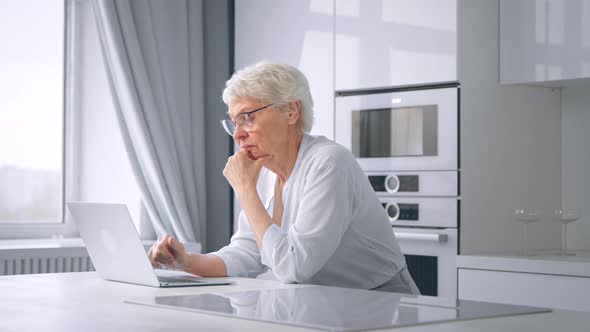 Pensioner manager woman types on grey laptop