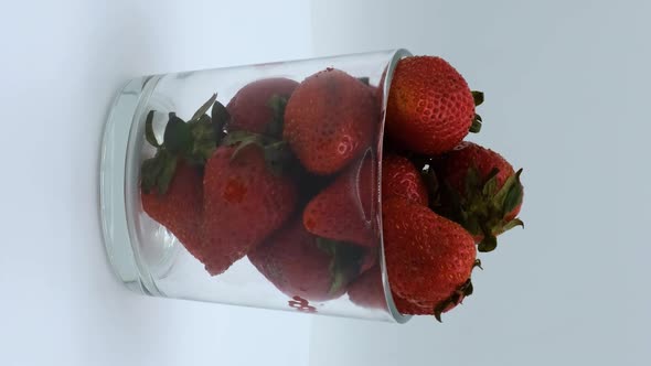 Vertical orientation video: Strawberries rotating on a white background. Strawberry ripe season