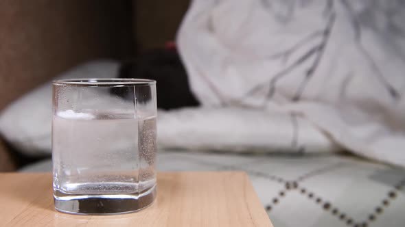 tablet dissolves in water, and on the background a man tossing and turning