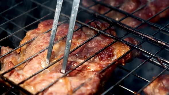 Cook Inserts Juicy Pork Meat Stake on Grill with Fork to Check