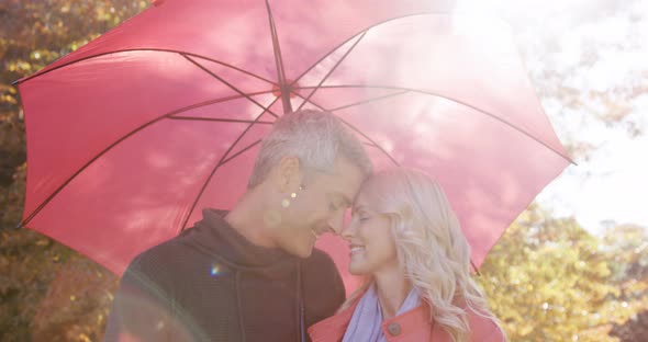 couple touching noses outdoors with umbrella
