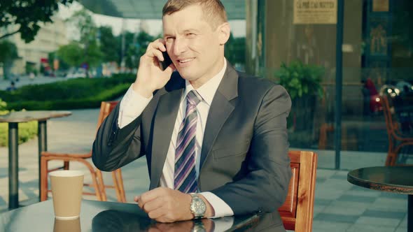 A Middleaged Businessman in Luxurious Clothes Answers the Call of His Mobile Phone the Business Man