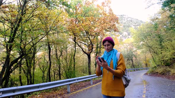 Woman with Backpack Using Smartphone Hiking In The Forest