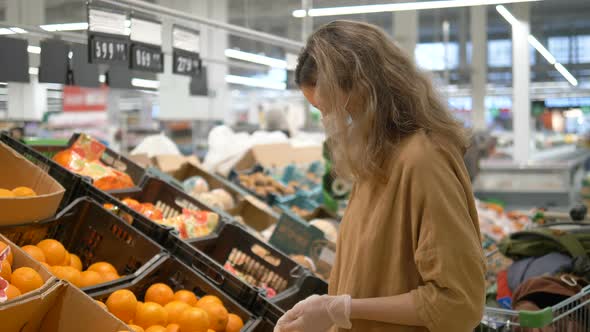 Woman in a Medical Mask and Gloves Selects Oranges in a Grocery Supermarket. Protection From the