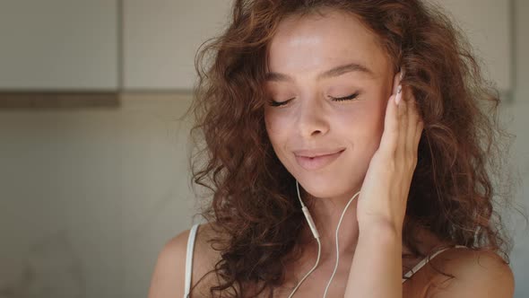 A Young Woman is Listening to Music and Smiling