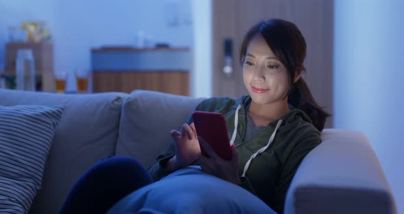 Woman use smart phone online and sit on sofa couch at home