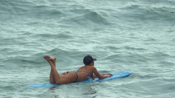 A young woman surfing in a bikini on a longboard surfboard.