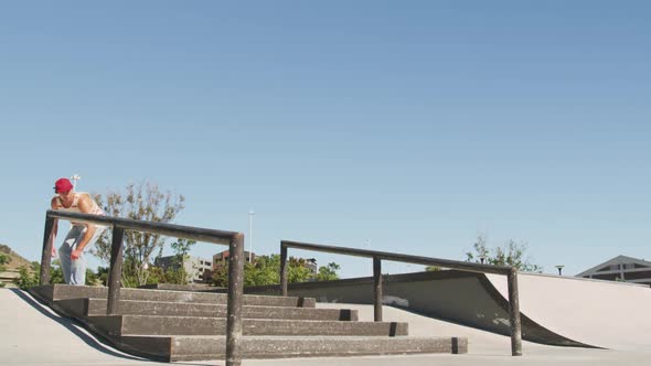 Caucasian man riding and jumping on skateboard on sunny day