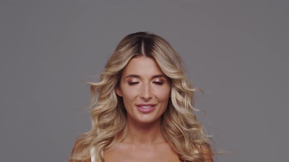 Studio portrait of young and beautiful blond woman over grey background.