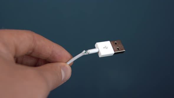 Torn USB Cable Close-up. A Man Holds a Torn Wire in His Hands. Wire Wear