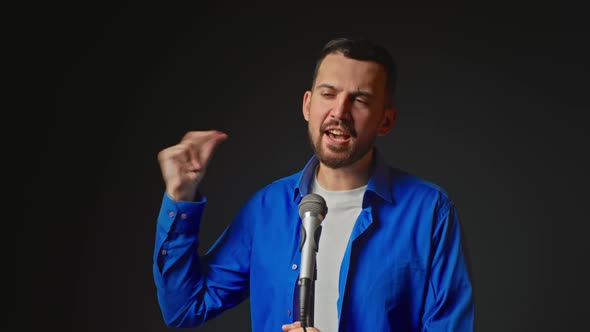 Portrait Of Singer Man Singing Song Standing Near Microphone Looking At Camera Posing In Dark Studio