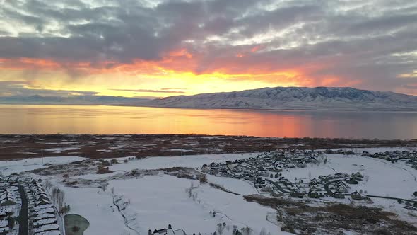 Aerial view flying over snow covered urban city landscape at sunset