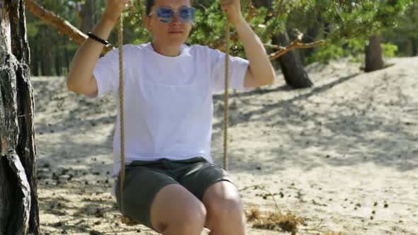 Young Woman Swinging on a Rope Swing on a Sunny Summer Day