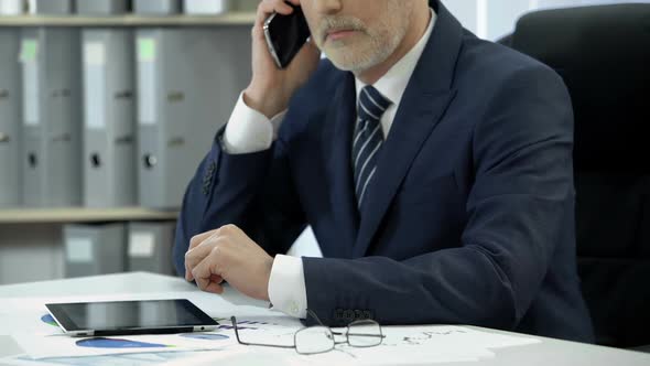 Businessman in Suit Working in Office, Dialing and Talking to Client Over Phone