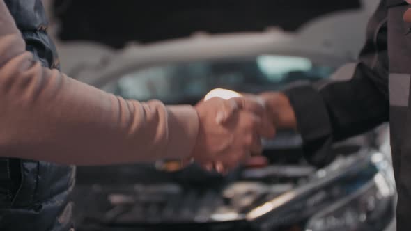 Unrecognizable Female Auto Mechanic Shaking Hands with Client