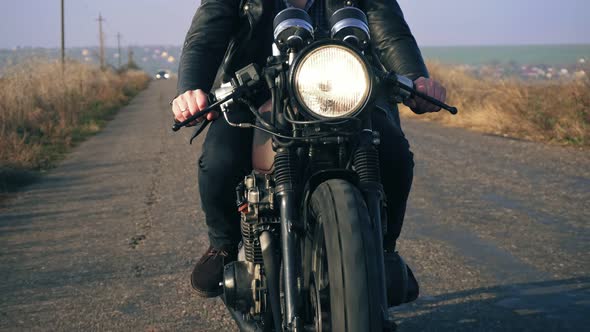 Front View of a Unrecognizable Man in Black Leather Jacket Riding Motorcycle on a Country Road