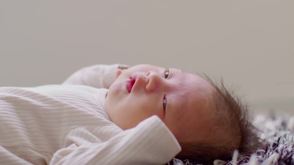 Side view happy newborn baby lying on a carpet looking at camera and smile comfortable and safety