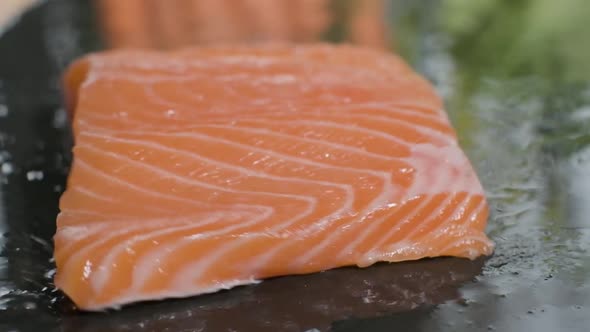 Fresh Salmon Fillet Falling Into Wet Black Stone Board. - close up, slow motion