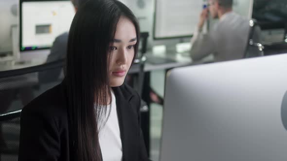 Attractive Asian Woman Working on Decktop Computer While Working in Big Open Space Office