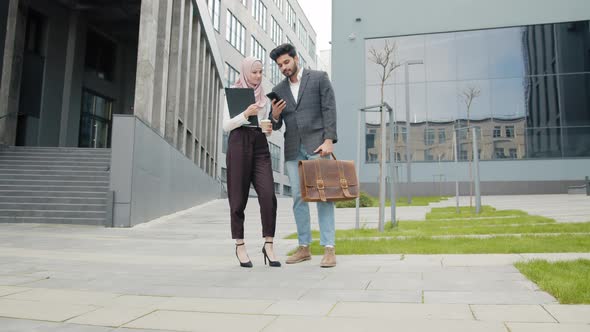 Muslim Man Showing Something on Mobile to Female Colleague