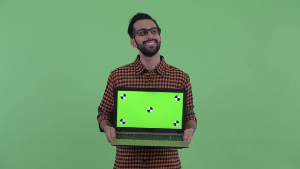 Happy Young Bearded Persian Hipster Man Thinking While Showing Laptop