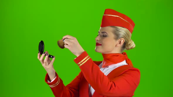 Stewardess Looks in the Mirror and Paints Her Face with a Tassel. Green Screen