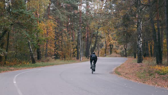 Professional Cyclist in Black Helmet and Cycling Apparel Intensively Training on Road Bike in Park