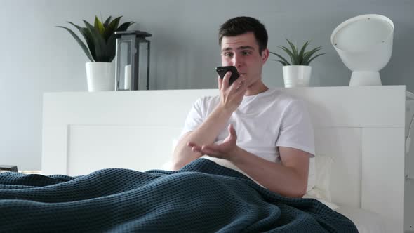 Angry Man Talking on Phone while Sitting in Bed