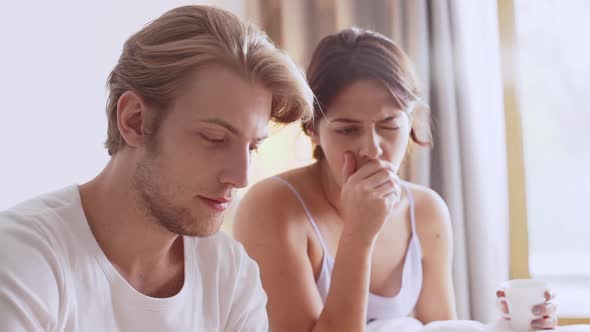 Charming Caucasian Female Yawning Sitting in Bed While Male Reading Morning Newspaper in Slowmotion