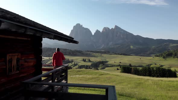 Man hiker walking in traditional wooden mountain hut at Alpe di Suisi meadows Dolomites, Italy