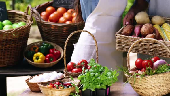 Mid section of couple holding fresh vegetables in basket