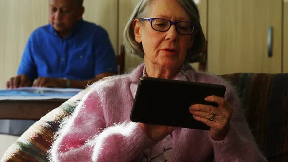 Senior woman using digital tablet in living room 4k