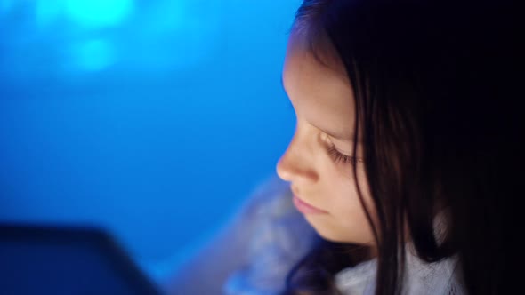 Girl Playing on Tablet in Bed