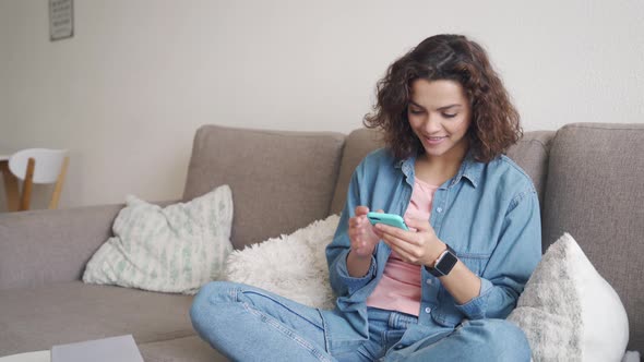 Hispanic Young Woman Using Smartphone App Sitting at Home