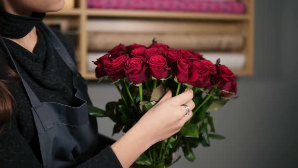 Focus on the Bunch of Red Roses Young Attractive Female Florist Arranging Bouquet of Beautiful Red