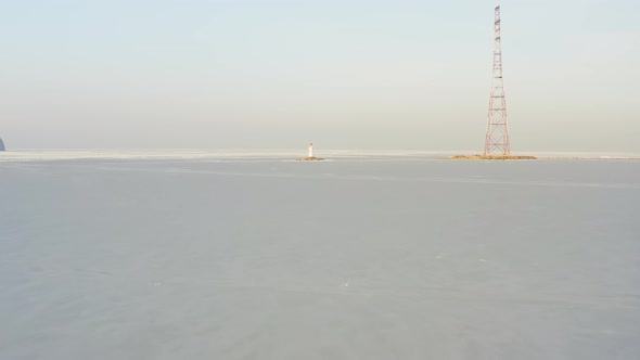 Flight Over the Frozen Sea and Drone View of Tokarevsky Lighthouse at Dawn